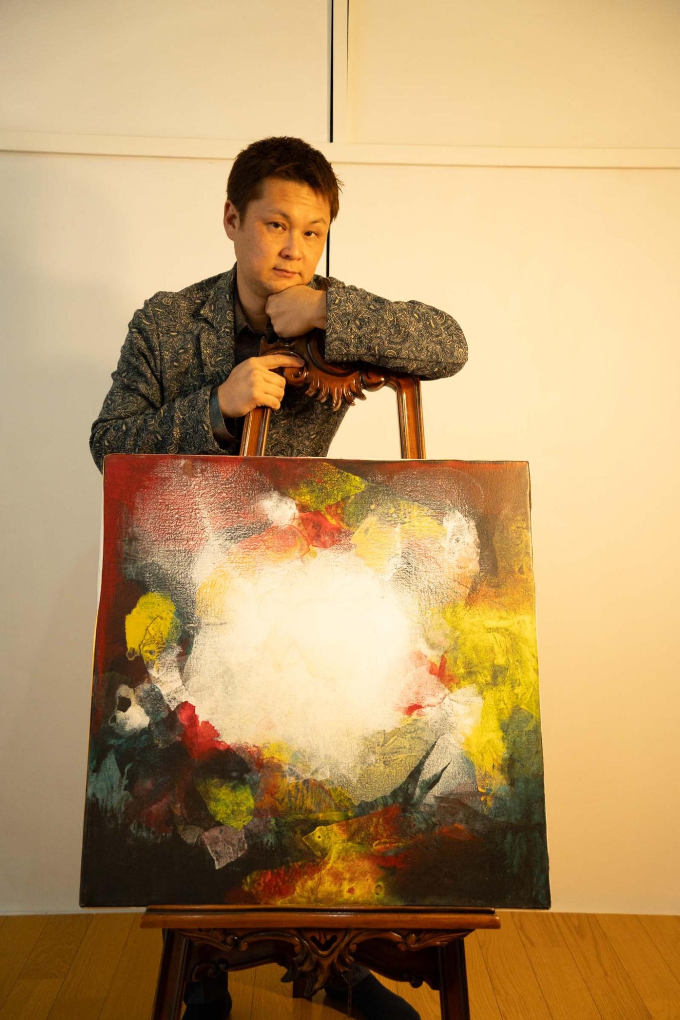 絵画の後ろで椅子に寄りかかるポーズ